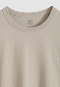 Μπεζ βαμβακερό t-shirt με στρογγυλή λαιμόκοψη και κοντά μανίκια. Διαθέτει διακριτικό μπάλωμα με το λογότυπο της Levi’s στο αριστερό στήθος. Μαλακή υφή, άνετη γραμμή.