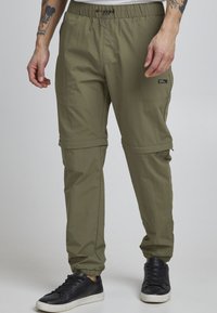 Olive green cargo pants made of lightweight fabric, featuring an elastic waistband, side pockets, and adjustable ankle cuffs.