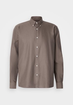 Ruskean nappipaidan, jossa on kauluskanta, pitkät hihat, hienovaraiset pystysuorat raidat ja valkoiset napit edessä.