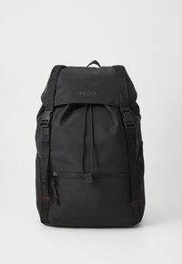 Black backpack featuring a drawstring closure, front zipper pocket, and branded straps. Made from durable material with a textured finish.