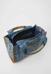 Denim bevásárlótáska bézs velúrbetétekkel; erős füllel és cipzáras belső zsebbel rendelkezik; mintás külsővel, amely texturált felülettel bír.