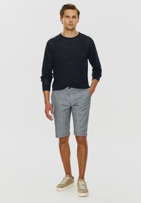 Marynarka w kolorze granatowym, wykonana z lekkiego materiału, z okrągłym dekoltem. Szare szorty w kratę z jasnoniebieskimi i żółtymi akcentami, długość do kolan. Wygodne sneakersy.