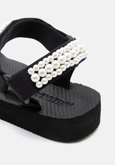 Μαύρο πλατφόρμα σανδάλι με υφή στη σόλα και λουράκι διακοσμημένο με τρεις σειρές λευκές ψεύτικες πέρλες.