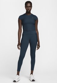 Crop top atletico blu navy a maniche corte abbinato a leggings a vita alta, realizzato in un materiale liscio ed elastico.