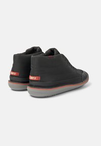 Black high-top shoes with a smooth fabric exterior, rubber sole, red accents, and visible stitching details on the sides and back.