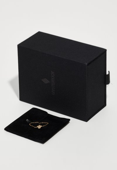 Black gift box with textured finish, featuring a slim black velvet pouch containing a gold chain bracelet with a decorative charm.