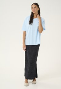 Light blue oversized t-shirt in soft cotton with a round neck, paired with a dark gray, textured, ankle-length skirt with a side slit.