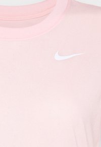 Růžové bavlněné tričko s kulatým výstřihem. Má bílé logo Nike na horní levé straně, hladkou strukturu a klasický střih.
