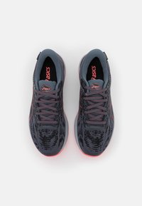 Paire de chaussures de course ASICS gris et corail vues de dessus avec un maillage à motifs et des lacets noués sur fond blanc.