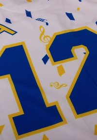 Witte stof met een blauw en geel grafisch ontwerp met grote cijfers "1" en "2," muzikale noten en geometrische patronen.