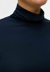Marineblå turtleneck lavet af blødt, strækbart stof; tætsiddende design med høj hals og glat tekstur. Ingen mønstre eller synlig hardware.
