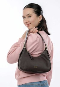 Borsa a tracolla in pelle marrone scuro con finitura testurizzata, forma curva, doppio manico superiore e dettagli in metallo dorato. Presenta una chiusura a zip e un dettaglio con logo.