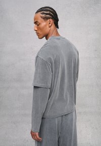 Grijze, oversized, korte mouwen top met een zachte textuur en een relaxte fit, met een ronde hals en verlaagde schouders, gecombineerd met bijpassende pantalons.