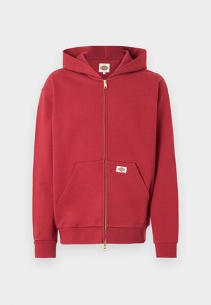Roter Kapuzenpullover mit Reißverschluss, Fronttaschen, gerippten Bündchen und einem kleinen Logopatch auf der Tasche sowie im Innenkragen.