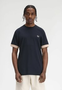 T-shirt blu navy in cotone, con accenti a righe sulle maniche e un piccolo logo sul petto. Tessuto morbido, scollo rotondo.