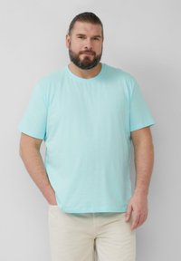 Lichtblauwe t-shirt met korte mouwen van zachte katoenstof, met een ronde halslijn en een relaxte pasvorm, gecombineerd met lichtgekleurde broek.