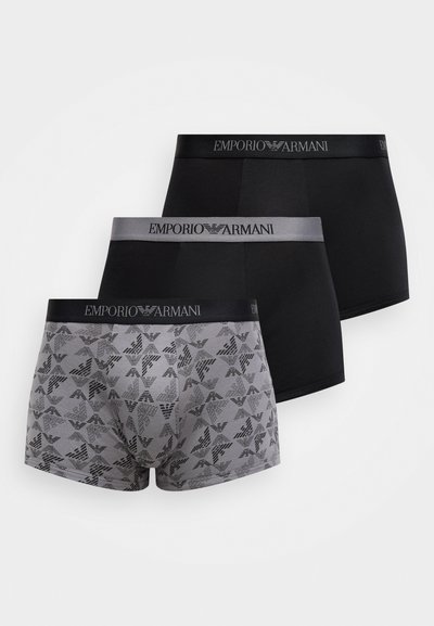 Trys vyriškų trumpikių poros: vienos vientisos juodos, vienos vientisos pilkos su logotipu ant juosmens, ir vienos pilkos su raštuotu dizainu.