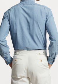 Ljusblå denimskjorta med långa ärmar, knäppta manschetter, en klassisk krage, i kombination med vita skräddarsydda byxor med två bakfickor.