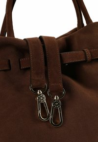 Sac à main en daim marron avec deux poignées supérieures, doté de fermoirs métalliques et d'un détail de bande cousue traversant l'ouverture. Texture lisse, design simple.