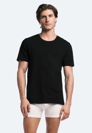 Mustahiile musta lyhythihainen t-paita puuvillakankaasta, jossa on pyöreä pääntie ja suora leikkaus. Mallilla on päällään valkoiset bokserit.