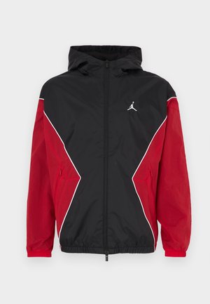 Black and red windbreaker jacket featuring a hood, zip front, white accents, and a small logo on the chest. Soft, lightweight fabric.