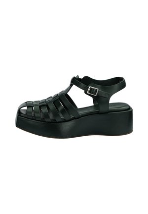 Black platform sandal with closed toe woven straps and adjustable buckle ankle strap, side view on white background.