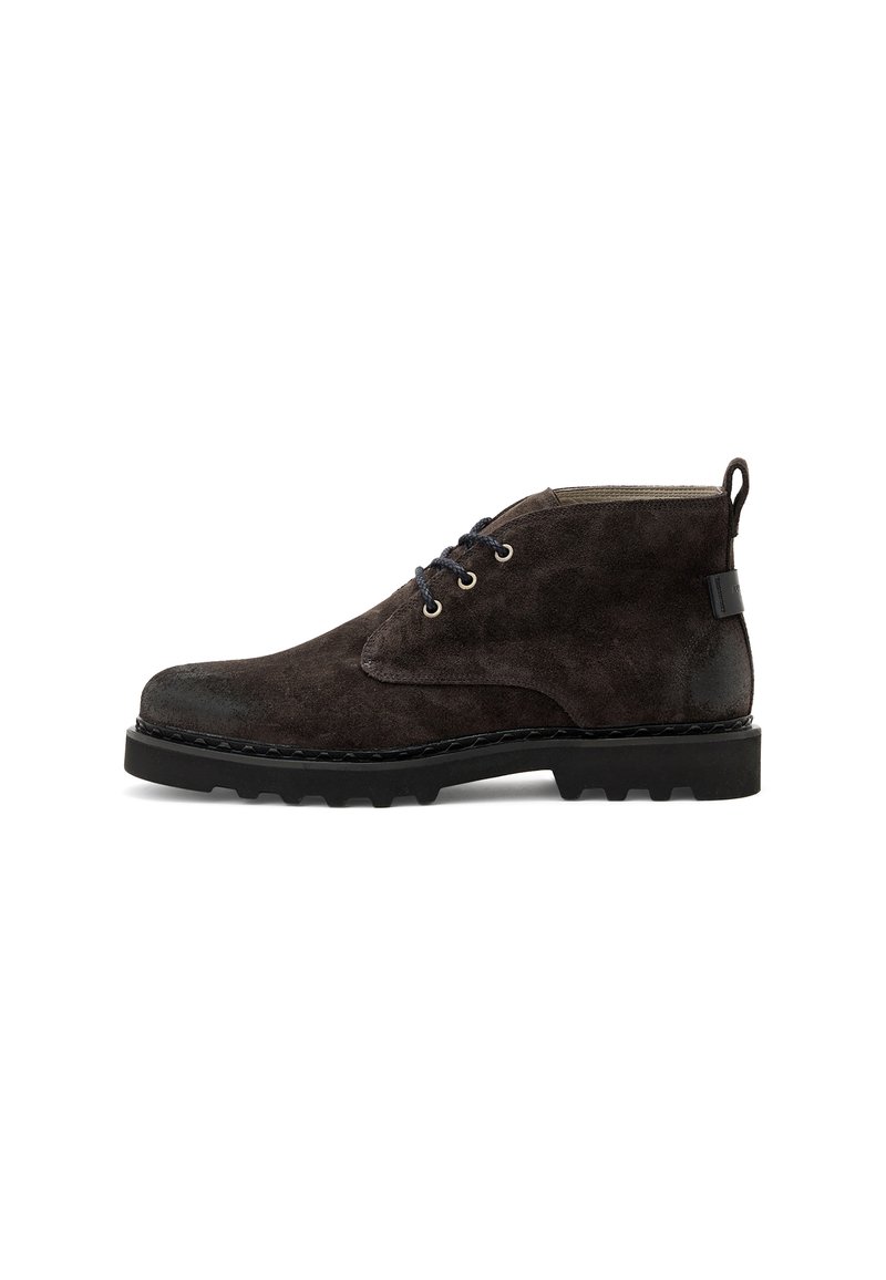 Stivale alla caviglia in suede marrone scuro con lacci neri, suola in gomma nera spessa e linguetta su sfondo bianco.
