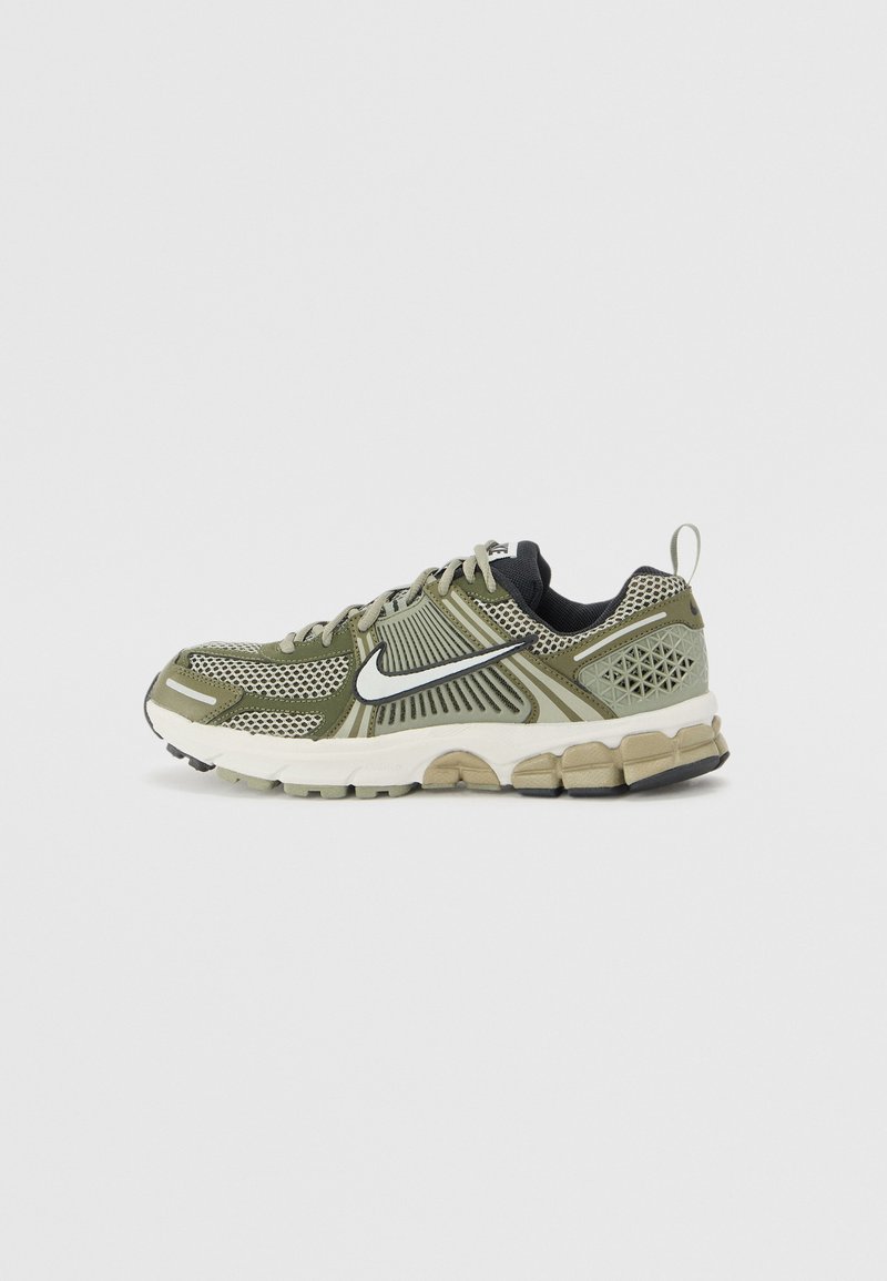 Sapatilha desportiva verde com upper de malha, detalhes texturizados, acabamentos pretos e sola almofadada, apresentando um destaque do logótipo na lateral.
