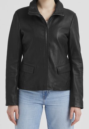 Chaqueta de cuero negra con mangas largas, cremallera frontal y bolsillos con solapas, usada con vaqueros azul claro, mostrada desde la mitad del cuello hasta las caderas.