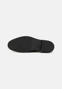 Sort skosål med et glat, fladt design. Har en afrundet tå og minimale mærker nær hælen. Holdbart gummimateriale.