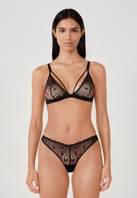 Conjunto de lencería de encaje negro que incluye un sujetador triángulo de material transparente y bordado floral, complementado con braguitas transparentes a juego.
