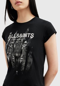 Camiseta de algodón negra con un estampado gráfico de la cara de un leopardo. Las mangas cortas y el cuello redondo enfatizan un diseño casual.