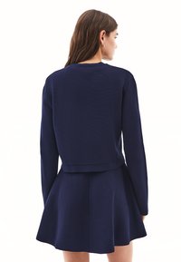 Granatowa sukienka w stylu skater z dopasowanym gorsetem i rozkloszowaną spódnicą, z długimi rękawami i teksturowanym materiałem. Minimalistyczny design z okrągłym dekoltem.