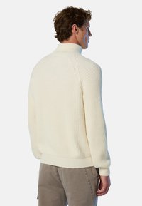 Maglione a coste color crema con colletto alto, caratterizzato da maniche lunghe e una vestibilità comoda. Tessuto a maglia testurizzato con cuciture visibili sulle spalle.