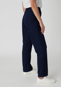 Navy blauwe sportbroek gemaakt van rekstof, met een elastische tailleband, rechte pijpen en zijnaad details.