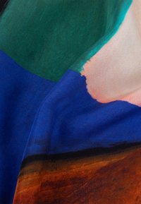 Meerkleurige sjaal met groene, blauwe en roze secties en een gladde textuur. Zichtbare penseelstreken op een lichte stof.
