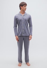 Γκρι βαμβακερή πιτζάμα που περιλαμβάνει μακρυμάνικο πουκάμισο με κουμπιά και τσέπη στο στήθος, καθώς και ταιριαστό παντελόνι, και τα δύο με λεία υφή.