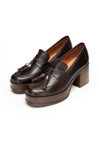 Braune Lederloafers mit Quasten, ausgestattet mit einem dicken Blockabsatz und einer glatten Textur. Detaillierte Nähte und silberne Hardware-Akzente.