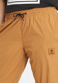 Gekleurde nylon shorts met een elastische tailleband, voorzien van een zwarte koord en een klein Timberland logo-opdruk aan de linkerkant.