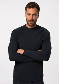 Dunkelblaues langärmeliges Sportshirt mit glatter Textur, Rundhalsausschnitt und eng anliegenden Ärmeln. Der Stoff zeigt minimale Markenkennzeichnung auf der Brust.
