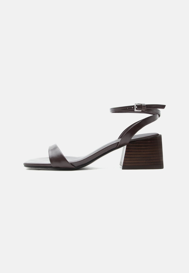 Sandale en cuir marron foncé avec bride à la cheville, petit talon bloc et bout ouvert, présentée de profil sur fond blanc.
