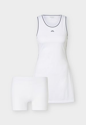 Witte mouwloze sportjurk met zwarte bies en logo, gecombineerd met witte nauwsluitende shorts, tentoongesteld tegen een effen achtergrond.