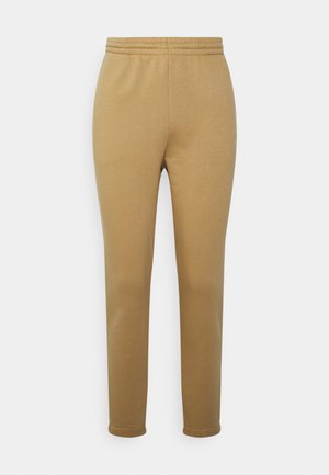 Calças de moletão bege com um cós elástico, design de perna afunilada e uma textura suave. Apresentam uma marcação discreta de lado.