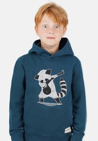 Tummansininen huppari, jossa mustavalkoinen pesukarhu graafinen kuvasto. Pehmeä kangas, pitkät hihat ja etupuolella kenguru-tasku.