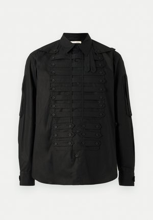 Chemise noire à manches longues avec boutons et sangles horizontales boutonnées d'inspiration militaire sur le devant et les manches, dotée d'un col pointu.