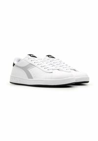 Sneaker in pelle bianca con dettagli grigi, lacci piatti e un tallone nero. Presenta dettagli perforati sui lati e una suola in gomma.