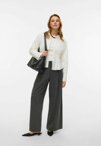 Biała koszula na guziki, szare szerokie spodnie, czarna pleciona torba oraz czarne mule z ostrymi czubkami. Gładkie tekstury i dopasowany krój.