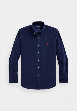 Navy blue button-down shirt made of corduroy, featuring long sleeves, a collar, and a small red logo on the left chest.