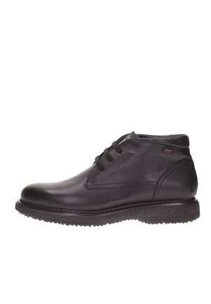 Bottes noires en cuir rembourrées avec une finition lisse, dotées de lacets et d'une semelle texturée pour une bonne adhérence. Embout arrondi et élancé, avec une accentuation minimaliste de la marque.