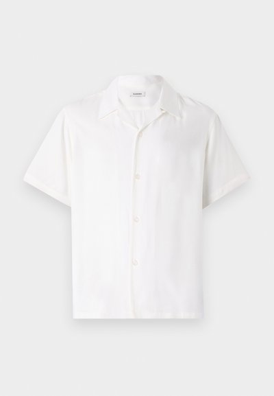 Rövid ujjú, sima anyagból készült fehér ing, álló nyakkal és ötféle gombbal záródó elülső résszel.